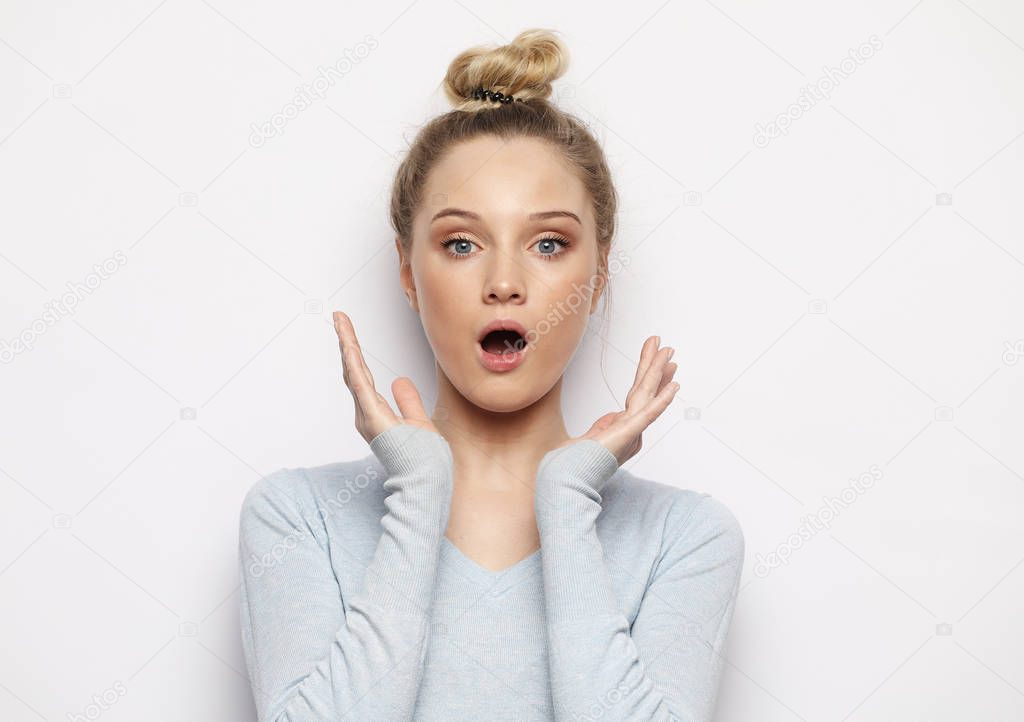 Indoor shot of stupefied shocked blonde woman keeps mouth widely opened, looks at camera, wears casual clothes