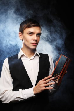 Profesyonel makyaj sanatçısı Studio, poz gölgeler paleti tutar. Duman arka planı.