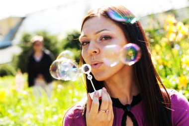 Kız darbe sabun köpüğü bir arka plan ot karşı