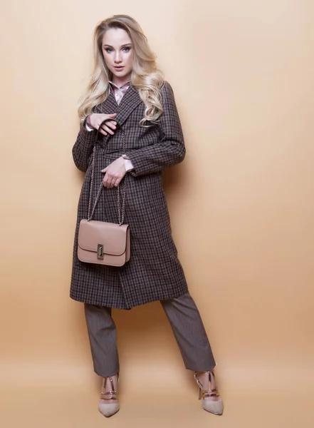 Мода, люди и образ жизни: женщина с длинными кудрявыми волосами носит кашемировое пальто и держит в руках сумочку. — стоковое фото