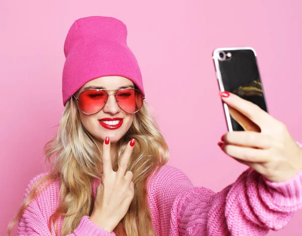 pembe arka plan üzerinde pinkl giyim eşyası Smartphone cep telefonu ile kendi kendine portre serin kız alarak fotoğraf yapar