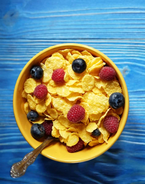 Cornflakes and different Berries - Blueberries and fresh Raspberries, blue wooden background. — Stock Photo, Image