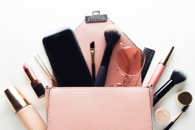 Kozmetik ürünler ve Acce ile açılmış pembe deri kadın çantası.