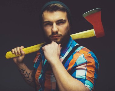 Ciddi oduncu. Büyük bir balta tutan ve kamera siyah arka plan karşı dururken bakarak kendine güvenen genç sakallı adam.