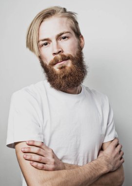 Yaşam tarzı ve insan konsepti: Genç sakallı adam beyaz arka planda kollarını kavuşturuyor