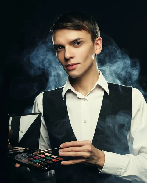 Professional makeup artist posing in studio, holds a palette of shadows and brush. — Stock Photo, Image