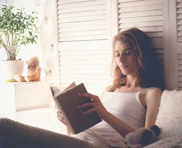 Lifestyle en mensen concept: Jonge blonde vrouw liggend in bed tijdens het lezen van een boek — Stockfoto