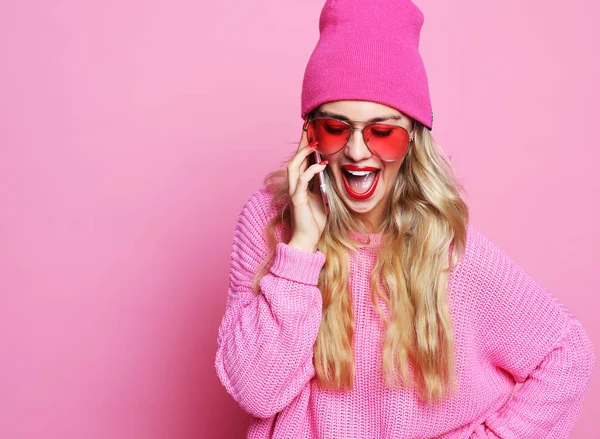Glücklich lächelndes Mädchen in pinkfarbener Kleidung auf rosa Hintergrund mit rosa Hut rosa Sonnenbrille und rosa Pullover. Lebensstilkonzept. — Stockfoto