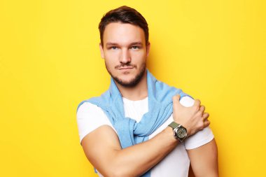 Sarı arka planda soyutlanmış genç yakışıklı bir adam resmi. Kameraya bakıyorum..