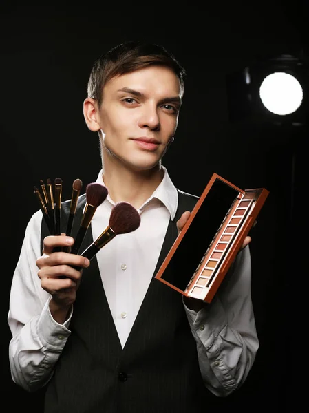 Beauty concept. Young male make up artist posing with make-up brushes and shadow palette — Stock Photo, Image