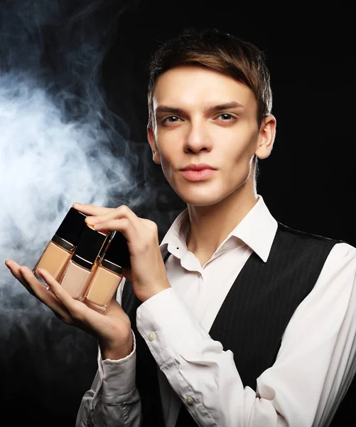 Концепция красоты. Молодой мужчина позирует с фундаментом для макияжа — стоковое фото