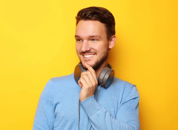 Életmód és az emberek koncepció: boldog fiatalember zenét hallgat fejhallgatóval sárga háttér — Stock Fotó
