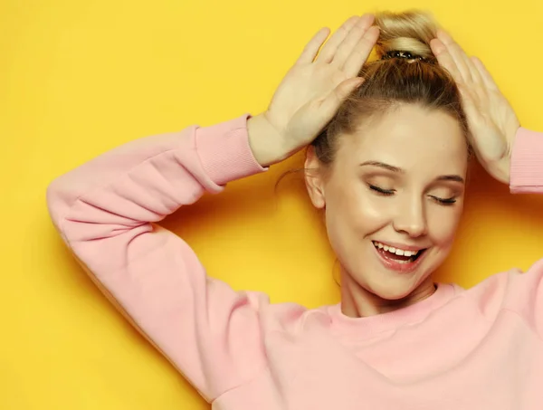 Closeup portrait of playful young pretty blond woman showing horns and making faces. Isolated on yellow background. — Stock Photo, Image