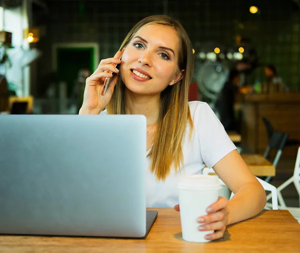 Üzleti wooman laptopot használ a kávézóban. Egy fiatal, gyönyörű lány ül egy kávézóban, és számítógépen dolgozik. Életmód és üzleti koncepció. — Stock Fotó