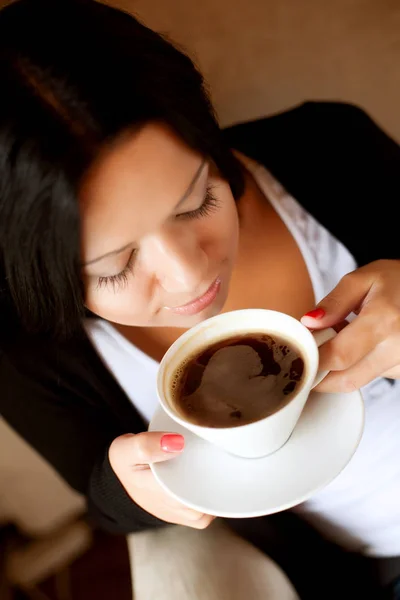 Молода жінка сидить у кафе п'є каву — стокове фото
