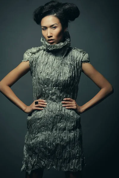 Beauty and fashion concept: young Asian fashion model in grey dress against black background — Stock Photo, Image