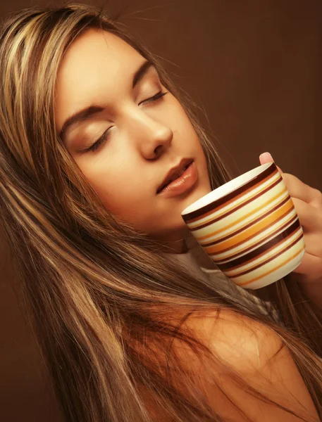 Retrato de uma mulher bonita com uma xícara de café em pé sobre o fundo bege — Fotografia de Stock