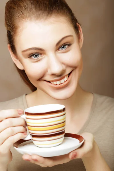 ベージュ色の背景上に立っているコーヒーのカップを持つ美しい女性の肖像画 — ストック写真