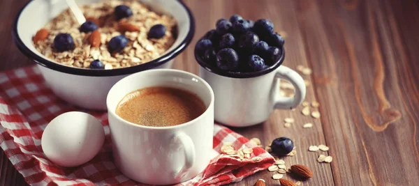 Ein gesundes Frühstück ist ein guter Start in einen neuen Tag. Haferbrei, Kaffee, Beeren und Nüsse auf einem Holztisch. — Stockfoto