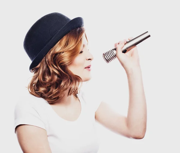 Estilo de vida e conceito de pessoas: modelo de beleza menina cantora usando chapéu com um microfone — Fotografia de Stock