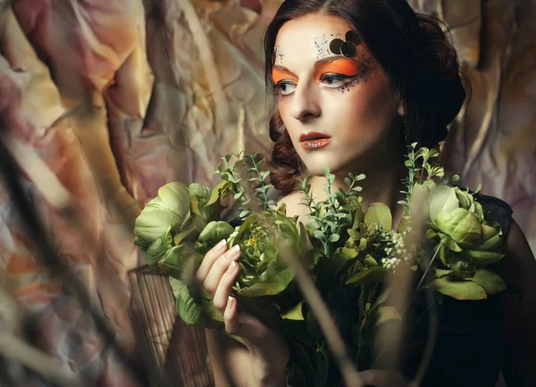 Крупним планом портрет рудоволоса жінка з яскравим креативним макіяжем, що тримає сухі квіти — стокове фото