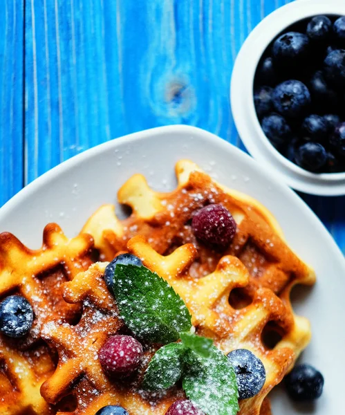 Geleneksel Belçika waffleları taze böğürtlenler ve beyaz tabakta şeker tozu, mavi ahşap arka plan. Düz konum, üst görünüm, kopyalama alanı. — Stok fotoğraf