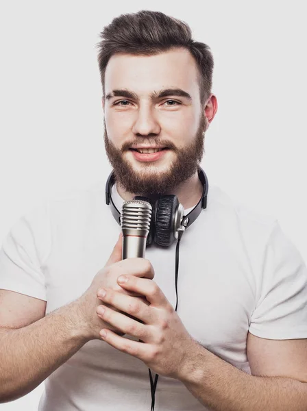Çocuk sallanıyor. Mikrofona şarkı söyleyen sakallı yakışıklı bir adamın görüntüsü. Beyaz arka planda sakallı çekici bir adamın duygusal portresi. — Stok fotoğraf