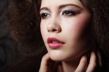 Kıvırcık saçlı ve akşam makyajlı güzel bir kadın. Mücevher ve Güzellik konsepti.