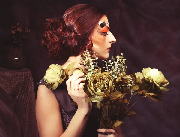 Retrato pelirrojo mujer con brillante creativo maquillaje celebración de flores secas, sesión de estudio — Foto de Stock