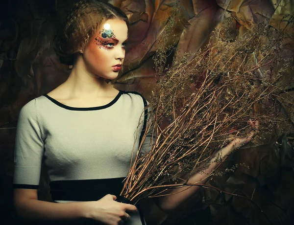 Beauty and art concept: Young woman with bright make up with dry branches — Stock Photo, Image