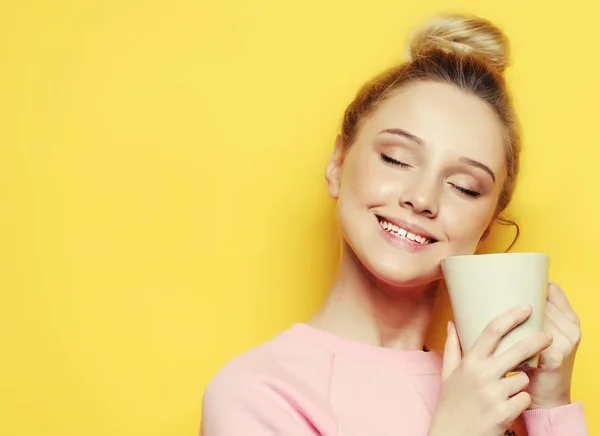 Молода жінка тримає білу чашку з чаєм або кавою, способом життя та концепцією їжі. Близько. Жовтий фон . — стокове фото