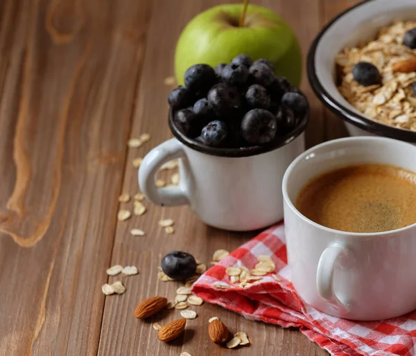 Um café da manhã saudável é um ótimo começo para um novo dia. Mingau de aveia, café, maçã, bagas e nozes em uma mesa de madeira. Vista superior. — Fotografia de Stock