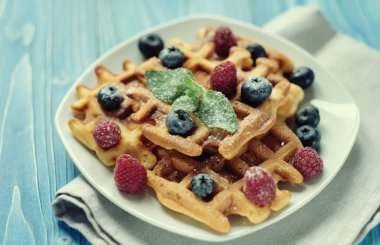 Yaban mersini, ahududu ve ahşap masa üzerine pudra şekeri ile Belçika waffle.