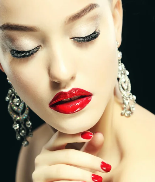 Портрет молодой красивой женщины с вечерним макияжем трогает ее лицо на черном фоне. Красные губы и ногти. Люксовые юбки и современная концепция модного макияжа, ювелирные заработки . — стоковое фото