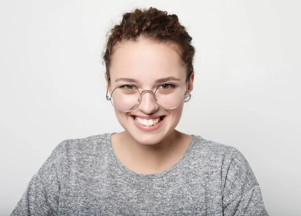 Retrato de alegre hermosa mujer gafas con aspecto complacido, lleva suéter casual gris, modelos en estudio sobre fondo blanco . — Foto de Stock