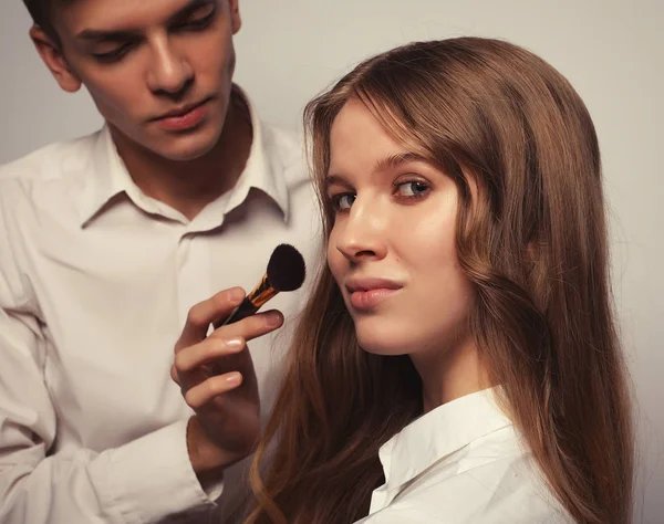 Joven hermosa mujer aplicando maquillaje por maquillador —  Fotos de Stock