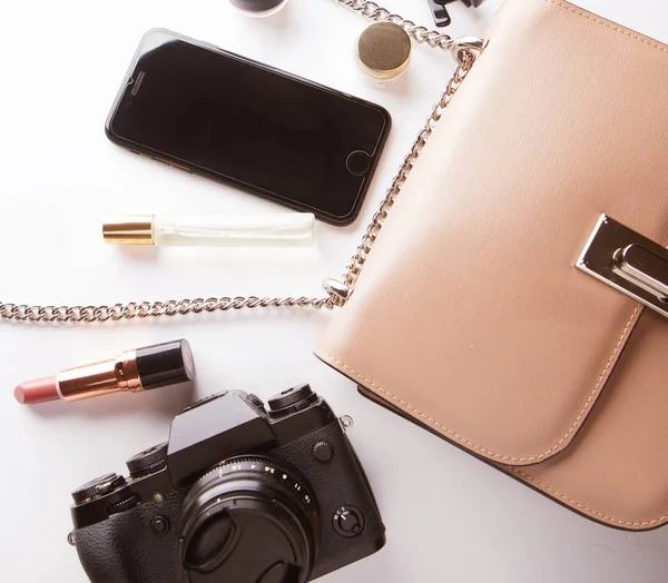 Pose plate de sac femme en cuir beige avec cosmétiques, accessoires, appareil photo et smartphone sur fond blanc. Concept beauté et mode. — Photo
