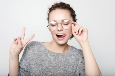 yanıp sönen, onun dilini giyimli raslantı kameraya, surat kıvırcık kadın gözlük takıyor. Pozitif kız içeride eğleniyor. Stüdyo vurdu.
