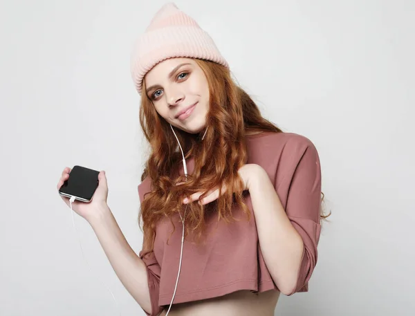 Životní styl a lidé koncept: mladá žena ve sluchátkách s chytrým telefonem poslech hudby. — Stock fotografie