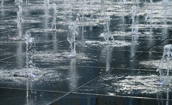 Hermosa fuente al aire libre, en la calle. Gotas de agua, chorros de agua congelados en el aire en vuelo contra el telón de fondo . — Foto de Stock