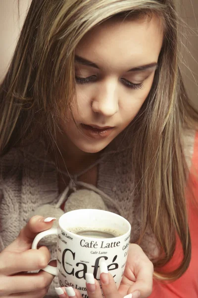 Retrato de uma mulher bonita com uma xícara de café em pé sobre o fundo bege, close up — Fotografia de Stock