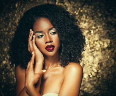afro saçlı genç zarif Afrikalı-Amerikalı kadın. Glamour makyaj. Altın arka plan.