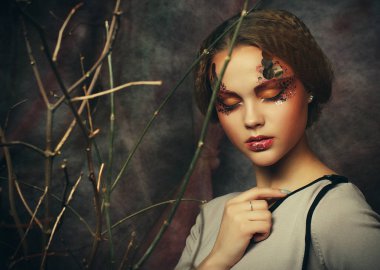 Güzellik ve sanat kavramı: kuru dalları ile parlak makyaj ile genç kadın