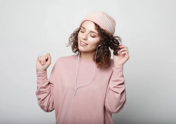 Lifestyle en mensen concept: Mooie jonge krullende vrouw in hoofdtelefoon luisteren naar muziek glimlachen met gesloten ogen — Stockfoto