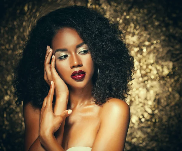 Giovane donna afro-americana elegante con capelli afro. Trucco glamour. Sfondo dorato . — Foto Stock