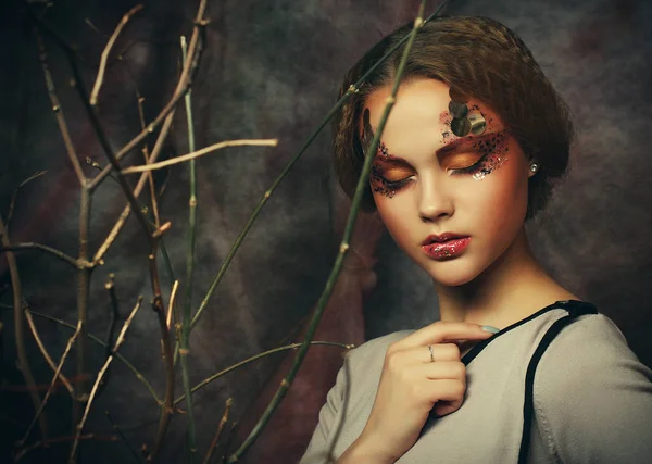 Ομορφιά και τέχνη έννοια: νεαρή γυναίκα με το έντονο make up με ξηρά κλαδιά — Φωτογραφία Αρχείου