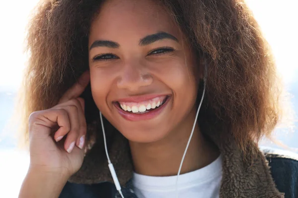 라이프 스타일 컨셉: 젊은 아프리카계 미국인 소녀가 핸드폰과 헤드폰을 사용하며 웃고 있다 — 스톡 사진