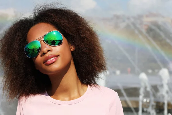 Jong Afrikaans amerikaans meisje in zonnebril, poseren buiten, gekleed casul, met kort volumineus haar. — Stockfoto