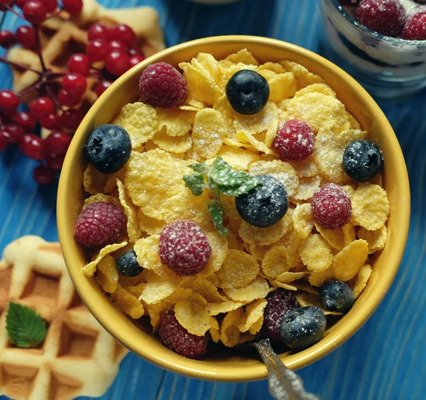 Desayuno saludable. Copos de maíz con frambuesas y arándanos, granola con yogur y bayas, obleas y leche. Un gran comienzo del día. Vista superior . — Foto de Stock