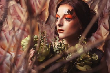 Güzellik ve sanat kavramı: kuru dalları ile parlak makyaj ile genç kadın